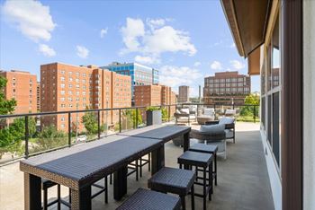 A balcony with a table and chairs overlooks a cityscape.